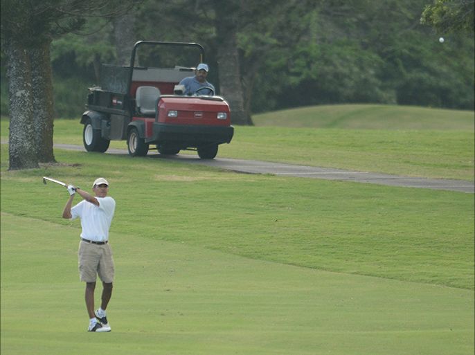 epa04005818 US president Barack Obama (R) looks on after hitting a ball (T-R) on the fairway as he approaches the 18th hole during his round of golf at the Mid-Pacific Country Club, in Kailua, Hawaii, USA, 01 January 2014. The US first family is on vacation in Hawaii until 05 January 2013. EPA