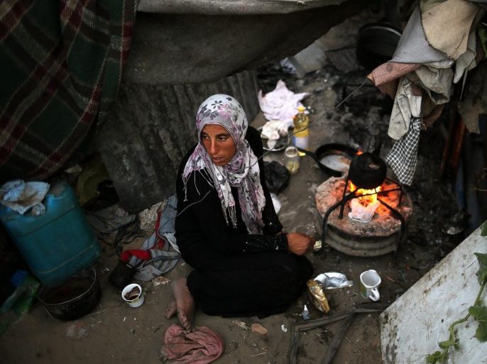 A Palestinian mother Na-aema Abu Shaweesh prepares tea on the fire in her home, in the east of Gaza City, the Gaza Strip, 03 June 2014. The Abu Shaweesh family consists of 11 people The family is one of many in Gaza that live in tents. They do not have any source of income and reports of human right's institutions said that more than 70 per cent of Gaza's people live below the poverty line set under international standards.