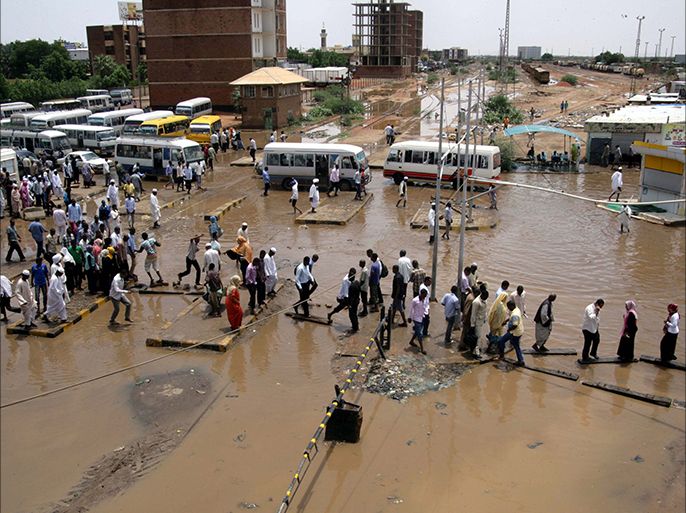 epa04339790 Sudanese people cross flooded streets in Khartoum, Sudan, 03 August 2014. According to local media more than 3000 homes have been destroyed by massive floods which affected over half of Sudan's states during Ramdan and the Eid al-Fitr holiday leaving almost 200 people injured. EPA/MORWAN ALI