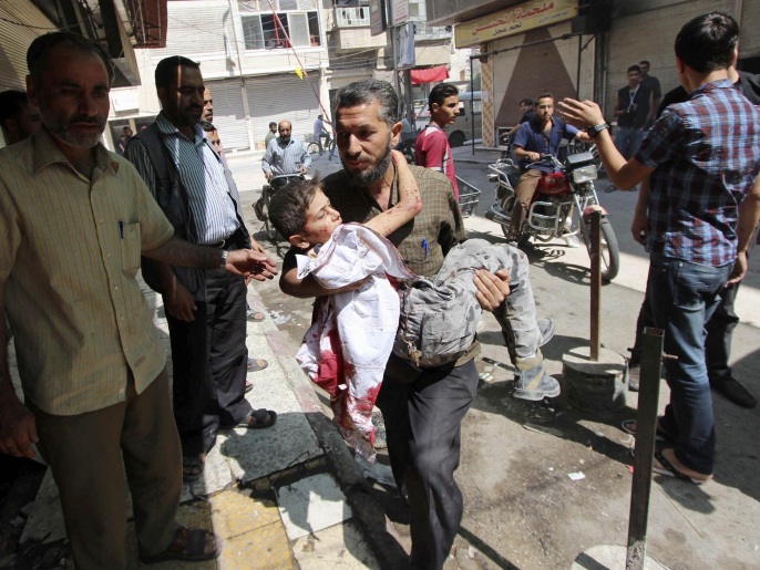 رجل يحمل طفلة جريحة جراء غارات النظام الأخيرة على مدينة دوما (رويترز)