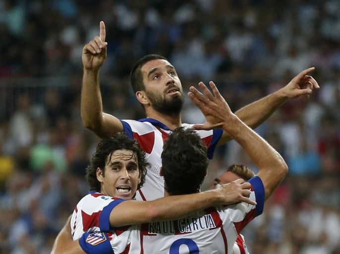 Atletico Madrid's Arda Turan (C) celebrates a goal with teammates Tiago (L) and Raul Garcia during their Spanish first division soccer match at Santiago Bernabeu stadium in Madrid September 13, 2014. REUTERS/Juan Medina(SPAIN - Tags: SPORT SOCCER)