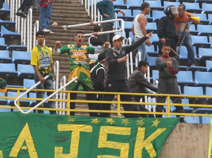 In this photo dated May 1, 2011, supporters of JS Kabylie gesture in the stands during disturbances at a soccer match against USM El-Harrah in Algiers, Algeria. Angry fans in Algeria pelted their own soccer team with rocks after they lost a game, killing the star player, Albert Ebosse, in the latest incident of fan violence in this North African country. Ebosse died after being hit in the head by an object thrown from the crowd at a top-flight league game in Algeria on August 23, 2014. Like much of the rest of the continent, Algeria's restless youth are passionate about soccer but with little other outlet for their daily frustration, violence haunts the games. (AP Photo/Anis Belghoul)