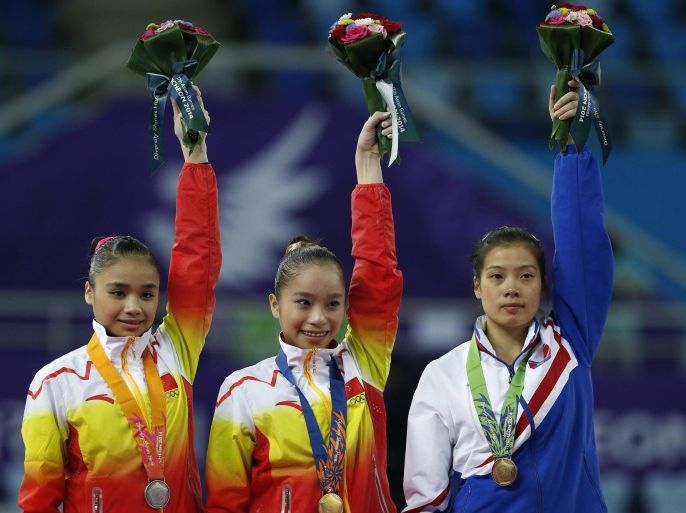 China's Yao Jinnan celebrates her gold medal along with silver medalist compatriot Huang Huidan (L) and bronze medalist North Korea's Kang Yong Mi (R) after the women's uneven bars final of the artistic gymnastics competition during the 17th Asian Games in Incheon September 24, 2014. REUTERS/Issei Kato (SOUTH KOREA - Tags: SPORT GYMNASTICS)