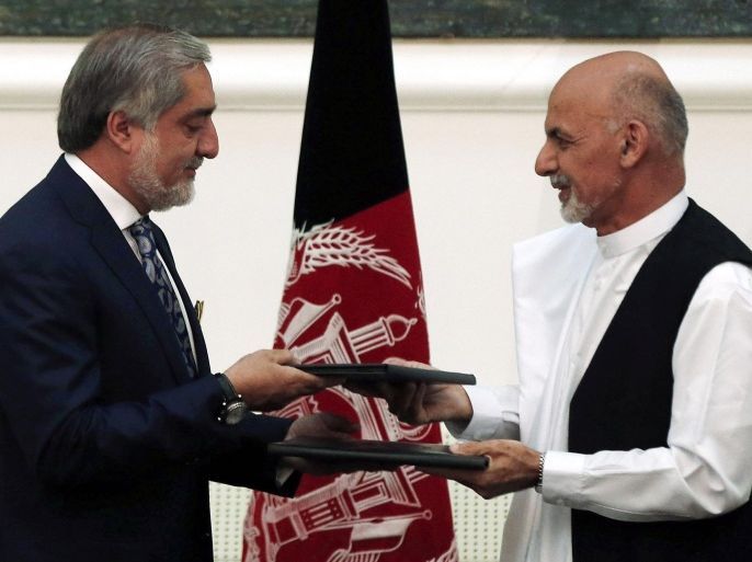 Afghan rival presidential candidates Abdullah Abdullah (L) and Ashraf Ghani exchange signed agreements for the country's unity government in Kabul September 21, 2014. Abdullah and Ghani signed a deal to share power in the unity government on Sunday, capping months of turmoil over a disputed election that destabilised the nation at a crucial time as foreign troops prepare to leave. Ashraf Ghani, a former finance minister, will be named president under the deal reached on Saturday night. REUTERS/Omar Sobhani (AFGHANISTAN - Tags: POLITICS TPX IMAGES OF THE DAY ELECTIONS)
