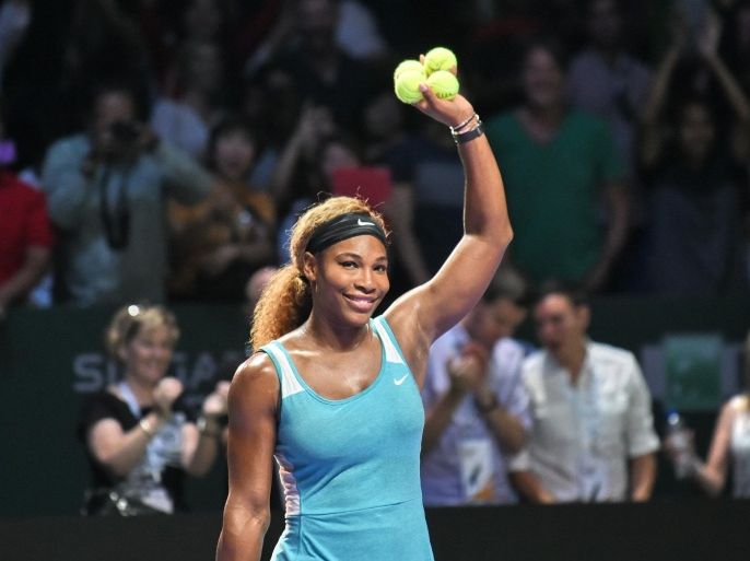 Two-time defending champion Serena Williams prepares to hit balls out to the audience after she beat Caroline Wozniacki of Denmark 2-6, 6-3, 7-6 (8/6) to reach the WTA Finals title match in Singapore on October 25, 2014. AFP PHOTO / ROSLAN RAHMAN