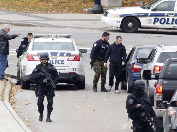 Police search cars and pedestrians as they leave the Alexandra Bridge and enter Gatineau, Quebec near the Parliament Buildings in Ottawa on Wednesday, Oct. 22, 2014. A Canadian soldier standing guard at a war memorial in the country's capital was shot to death and heavy gunfire then erupted inside Parliament. One gunman was killed, and police said they were hunting for as many as two others. The attack immediately raised the specter of terrorism, with Canada already on alert because of a deadly hit-and-run earlier in the week against two Canadian soldiers by a man who police say was fired up with radical Muslim fervor. (AP Photo/The Canadian Press, Patrick Doyle)