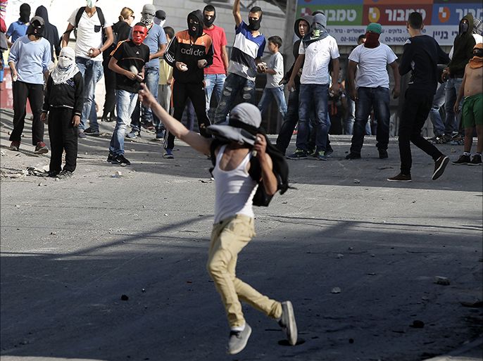A Palestinian protester throws stones towards Israeli police (unseen) in front of his comrades during clashes in a suburb of East Jerusalem on October 23, 2014. Clashes started after Israeli police flooded flashpoint Arab neighbourhoods a day after a deadly Palestinian car attack killed a baby in Jerusalem. AFP