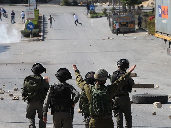 Israeli soldiers gesture near stones thrown by Palestinians during a demonstration, against Israeli restrictions around the al-Aqsa mosque in Jerusalem,  called by Hamas in the West Bank town of Hebron on October 24, 2014. Israel deployed police in force in Jerusalem for weekly Muslim prayers and restricted access to a flashpoint mosque, after a deadly attack by a Palestinian sent tensions soaring. AFP PHOTO/ HAZEM BADER