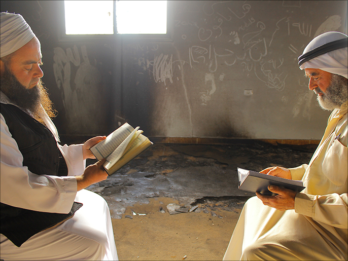 ‪شيخان يقرآن القرآن بمسجد أبو بكر الصديق الذي أحرقه مستوطنون قبل أقل من شهر‬  (الجزيرة)