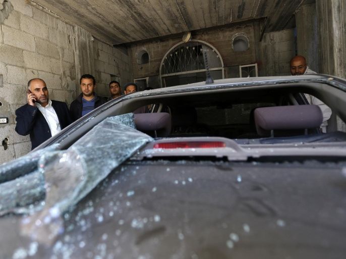 Fayez Abu Eitta (L), a Fatah leader in Gaza, speaks on the phone as he inspects the damage to his car in the parking lot of his home in Beit Lahya, northern Gaza Strip on November 7, 2014. At least 10 explosions hit houses and cars belonging to members of the Fatah movement of Palestinian president Mahmud Abbas in Gaza on Friday, an AFP correspondent and witnesses said. AFP PHOTO / MOHAMMED ABED