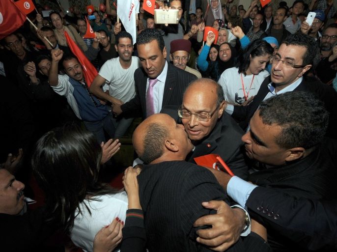 Tunisian outgoing President Moncef Marzouki (LC), who seeks re-election, greets supporters before his first campaign meeting in Tunis on November 2, 2014. A rights activist exiled under deposed president Zine El Abidine Ben Ali, Marzouki allied himself with the Islamist Ennahda party and he is seen as having prevented the country being split between secular and Islamist camps. Twenty-seven candidates are standing for president in Tunisia on November 23. AFP PHOTO / FETHI BELAID