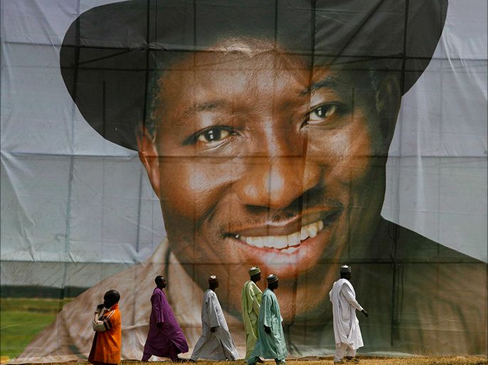epa02694086 (FILE) A photograph dated 10 February 2011 shows Nigerian men walking in front of a banner of president Goodluck Jonathan at a Peoples Democratic Party (PDP) campaign rally in Kaduna north western Nigeria. Nigeria's president has been declared the winner of the oil-rich nation's election although there have been opposition riots in the north of the country. Election chairman Attahiru Jega announced results 18 April 2011 that showed President Goodluck Jonathan easily beat his nearest rival, former military ruler Muhammadu Buhari. EPA