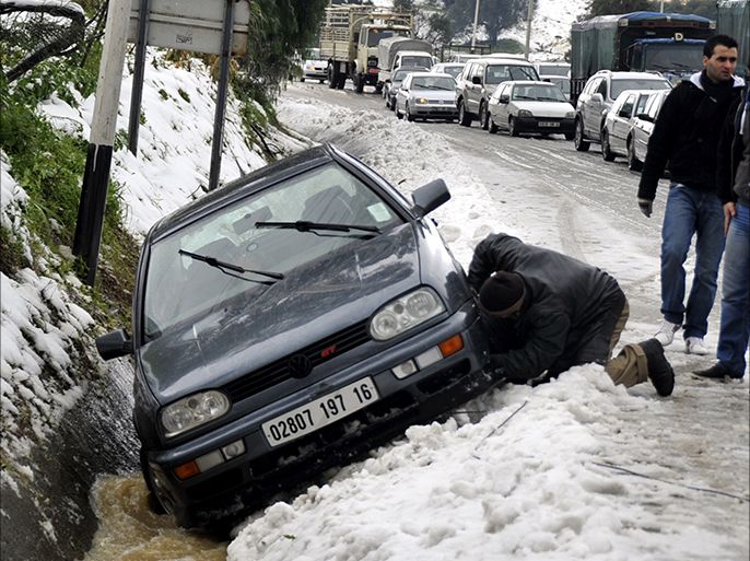 epa03094704 An Algerian leans on his vehicle tyres, after it slid from the main road following snow fall in Algiers, Algeria, 06 February 2012. Freezing cold combined with snowstorms continued to claim lives across Europe, as the blanket of snow reached as far south as North Africa with a cold wave hitting Algeria, Libya and Tunisia EPA/STR