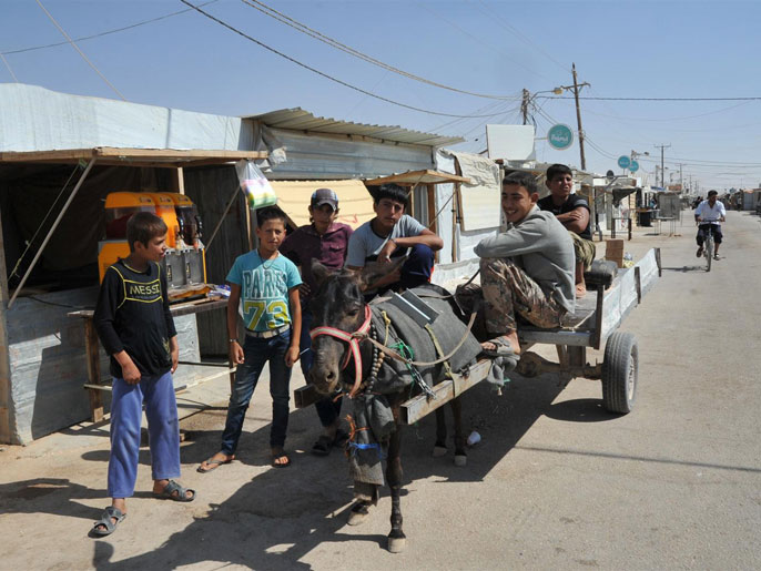 ‪‬ أطفال يعملون بنقل البضائع والأشخاص على عربة يجرها حمار(الجزيرة)
