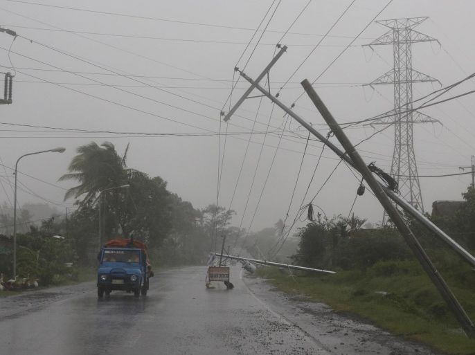 Motorists pass by toppled electrical posts due to strong winds brought by Typhoon Hagupit in Camalig, Albay province, eastern Philippines on Sunday, Dec. 7, 2014. Typhoon Hagupit knocked out power in entire coastal provinces, mowed down trees and sent more than 650,000 people into shelters before it weakened Sunday, sparing the central Philippines a repetition of unprecedented devastation by last year's storm.(AP Photo/Aaron Favila)