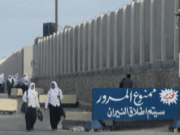 Egyptian schoolgirls pass by a sign in Arabic reading 'no passing, will open the fire al-Arish in the Sinai peninsula on November 17, 2014. With soldiers firing warning shots to herald the nightly curfew and jihadist militants beheading informants, Sinai's residents find themselves caught in the middle of Egypt's 'war on terror'. AFP PHOTO / STR