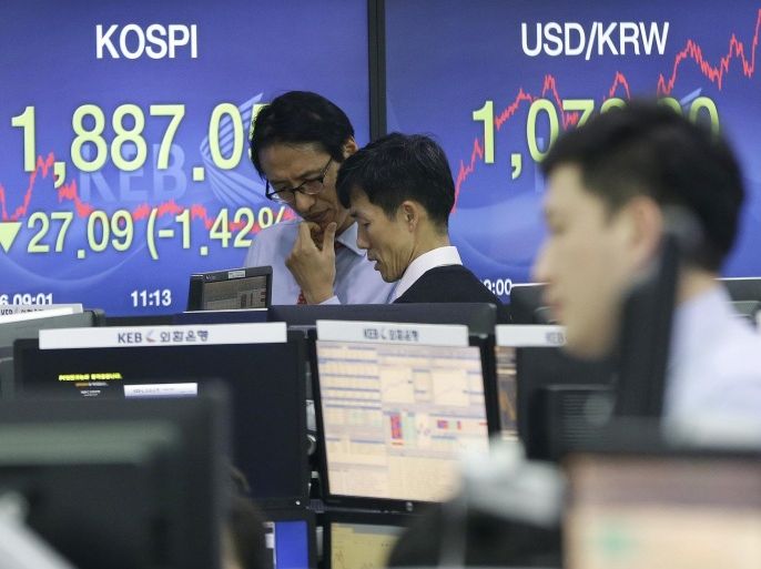 Traders work in front of screens showing the Korea Composite Stock Price Index (KOSPI) and the exchange rate between the U.S. dollar and the South Korean won at the Korea Exchange Bank, right, at the Korea Exchange Bank headquarters in Seoul, South Korea, Friday, Jan. 16, 2015. Asian stocks were sharply lower Friday after a surprise move by the Swiss National Bank to abandon its efforts to keep its currency artificially cheap shocked the market. South Korea's Kospi fell 1.4 percent to 1,887.10. (AP Photo/Ahn Young-joon)
