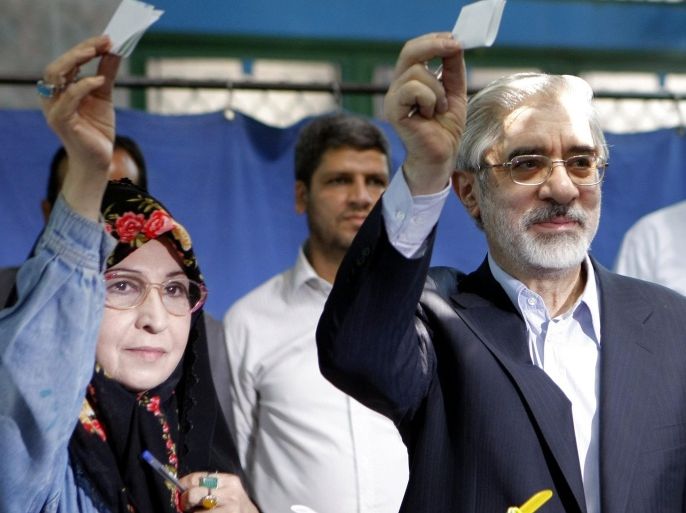 Former Iranian prime minister and presidential candidate Mir Hossein Mousavi (R) and his wife Zahra Rahnavard (L) show their ballots before voting at a polling station in Ershad mosque, southern Tehran, on June 12, 2009. Iranians poured into polling stations to vote in a close-fought presidential race which has seen moderate ex-premier Mir Hossein Mousavi emerge as the main challenger to incumbent hardliner Mahmoud Ahmadinejad.