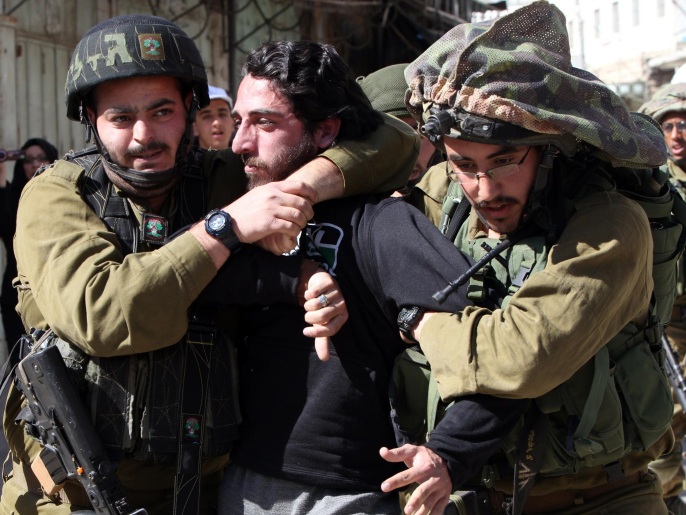 جنديان من الاحتلال يعتقلان شابا فلسطينيا أثناء مسيرة اليوم بالخليل (غيتي/الفرنسية)