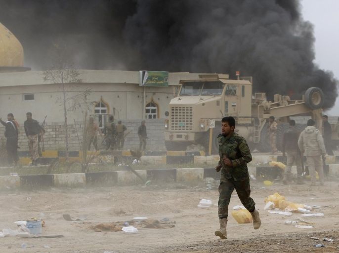 A Shi'ite fighter known as Hashid Shaabi, runs as smoke rises from an explosives-laden military vehicle driven by an Islamic State suicide bomber which exploded during an attack on the southern edge of Tikrit March 12, 2015. Iraqi security forces and mainly Shi'ite militia exchanged fire sporadically with Islamic State fighters in Tikrit on Thursday, a day after they pushed into Saddam Hussein's home city in their biggest offensive yet against the militants. REUTERS/Thaier Al-Sudani (IRAQ - Tags: POLITICS CIVIL UNREST CONFLICT MILITARY)