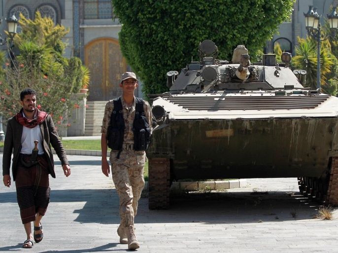 Yemeni soldiers loyal to the Huthi Shiite militia walk past a tank inside the vicinity of the presidential palace on February 25, 2015 in the capital Sanaa. Relatives of a Yemeni woman kidnapped with a French female development worker in Sanaa said they had sought help from tribal leaders and Shiite militiamen to secure their release. Yemen has descended into chaos since the Huthis swept into Sanaa last year from their northern stronghold. AFP PHOTO / MOHAMMED HUWAIS