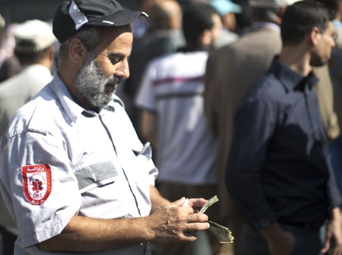 A Palestinian employee of the former Hamas government counts his money outside a post office in Gaza City on October 29, 2014 after receiving 1,200 US dollars which is part of his wages that has been delayed for months. The Palestinian national unity government headed by prime minister Rami Hamdallah sent the previous day roughly 30 million dollars by car across the Erez border crossing from the West Bank to the Gaza Strip to pay 24,000 former employees. AFP PHOTO / MAHMUD HAMS