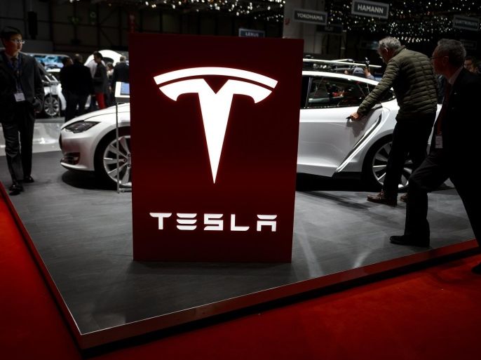 Visitor are seen at the booth of US electric carmaker Tesla Motors, during the press day of the Geneva Car Show on March 4, 2015 in Geneva. AFP PHOTO / FABRICE COFFRINI