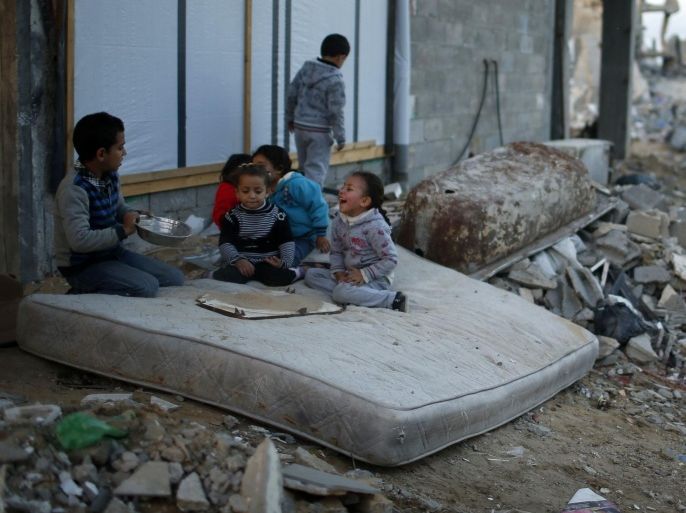 Palestinian children play on a mattress near the ruins of houses which witnesses said were destroyed by Israeli shelling during the most recent conflict between Israel and Hamas, in the east of Gaza City December 1, 2014. According to housing minister Mufeed al-Hasayna, Gaza needs 8,000 tonnes of cement a day to meet demand. A new system set up with the United Nations to comply with Israeli requirements lets through at most 2,000, he said. At that rate, reconstruction would take more than 30 years, said Hasayna, one of four members of the unity government based in Gaza rather than the West Bank. Since the war, electricity has been partially restored so that power is now cut for only eight hours a day. Sewage and water treatment plants are mostly working again, although there is still almost no drinking water. But in terms of clearing the vast mountains of rubble and mangled steel, rebuilding homes and patching up smashed roads, bridges and other infrastructure, next to nothing has happened. REUTERS/Mohammed Salem (GAZA - Tags: POLITICS CIVIL UNREST SOCIETY BUSINESS CONSTRUCTION)