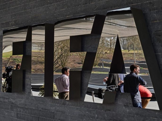 Member of the media wait next to a logo of the Worlds football governing body, at the FIFA headquarters in Zurich, prior to a press conference of FIFA President Sepp Blatter on March 20, 2015, closing a two-day meeting to decide the dates of the 2022 World Cup in Qatar. AFP PHOTO / MICHAEL BUHOLZER