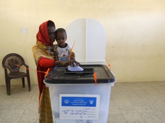A Sudanese woman holding her child casts her vote at a polling station in Khartoum on April 15, 2015. Sudanese are voting in elections boycotted by the mainstream opposition that are expected to extend the quarter-century rule of President Omar al-Bashir, who is wanted on war crimes charges. AFP PHOTO / PATRICK BAZ