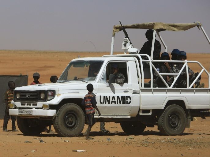 Members of the UN-African Union mission in Darfur (UNAMID) drive past children inside the Zam Zam camp for Internally Displaced People (IDP), North Darfur, on April 9, 2015. Sudan heads to the polls next week in elections widely expected to extend President Omar al-Bashir's quarter-century rule, despite his indictment for alleged war crimes, continued unrest and a faltering economy. AFP PHOTO / ASHRAF SHAZLY