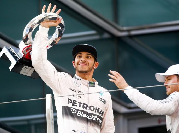 British Formula One driver Lewis Hamilton (L) of Mercedes AMG GP lifts his trophy after winning the Chinese Formula One Grand Prix as second placed German Formula One driver Nico Rosberg of Mercedes AMG GP waves at fans at the end of the Chinese Formula One Grand Prix at the Shanghai International circuit in Shanghai, China, 12 April 2015.