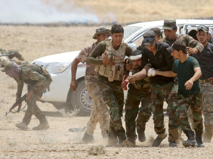 ‪عناصر من المليشيات يسعفون أحد جرحاهم في اشتباكات الأنبار ضد تنظيم الدولة‬ (رويترز)