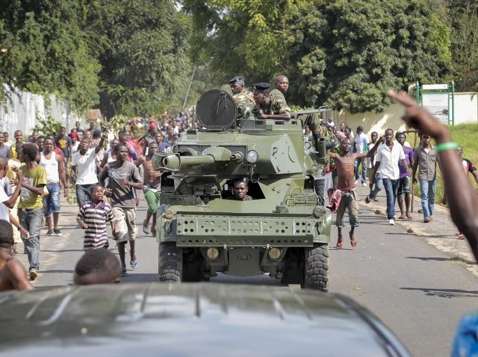 Burundi army soldiers ride through the streets in an armored vehicle as demonstrators celebrate what they perceive to be an attempted military coup d'etat, in the capital Bujumbura, Burundi Wednesday, May 13, 2015. Police vanished from the streets of Burundi's capital Wednesday as thousands of people celebrated a rumored coup attempt against President Pierre Nkurunziza. (AP Photo/Berthier Mugiraneza)