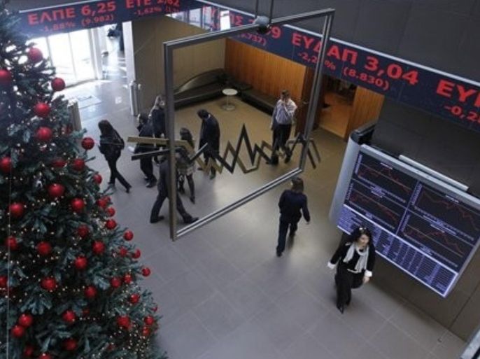 People view the screens showing financial stocks, behind a Christmas tree at the Athens Stock Exchange, Friday, Dec. 9, 2011. European leaders are examining tougher budget enforcement rules to try to stem a eurozone debt crisis that is threatening the euro. The values of shares on the Greek bourse has fallen sharply throughout the year amid a deepening recession.