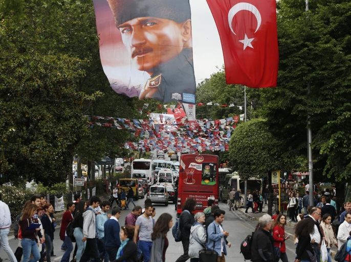 In this Thursday, May 28, 2015, photo, a portrait of Turkish Republic founder Mustafa Kemal Ataturk, top left, and a Turkish flag, right, backdropped by Turkish parties' banners and flags fly over a street in Istanbul, Turkey. Turkey will hold a general election on June 7. (AP Photo/Lefteris Pitarakis)