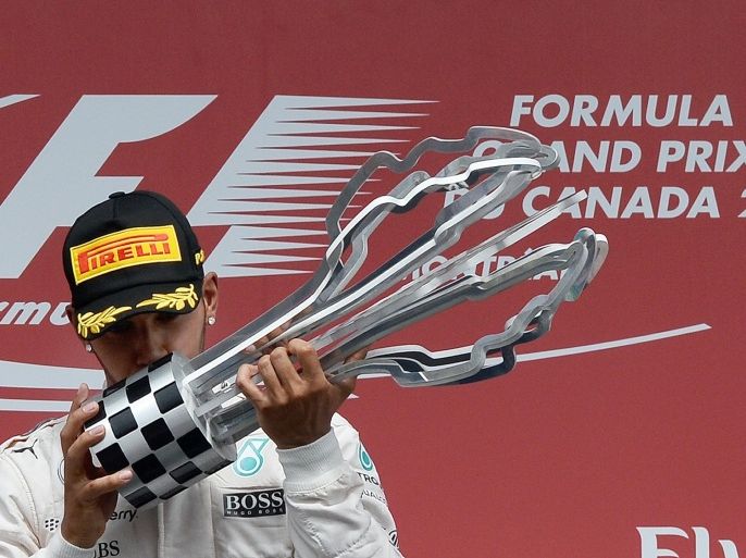 Mercedes AMG Petronas British driver Lewis Hamilton kisses the trophy on the podium at the Circuit Gilles Villeneuve in Montreal on June 7, 2015, after winning the Canadian Formula One Grand Prix. AFP PHOTO/JEWEL SAMAD