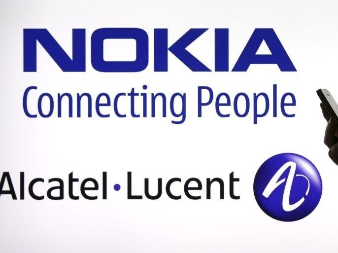 A woman holds a smartphone in front of a screen displaying both Nokia and Alcatel-Lucent logos in this file photo illustration shot in Paris, France, April 14, 2015. Alcatel-Lucent is expected to hold its AGM this week. REUTERS/Benoit Tessier/FilesGLOBAL BUSINESS WEEK AHEAD PACKAGE - SEARCH "BUSINESS WEEK AHEAD MAY 25" FOR ALL IMAGES