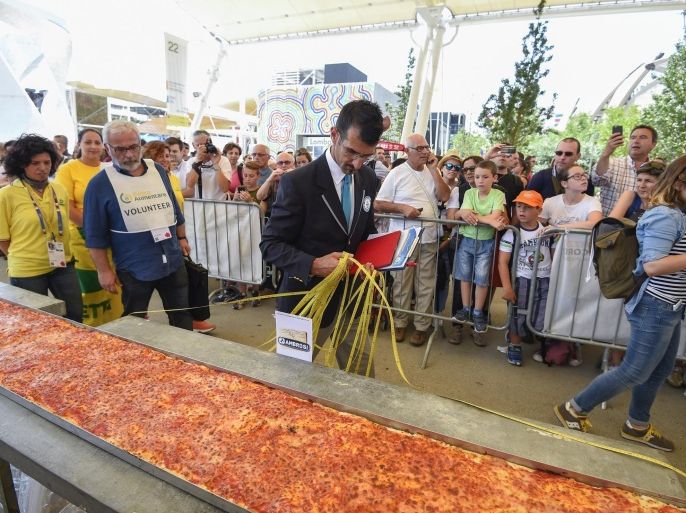 Italy's judge of the 'Guinness World Record' Lorenzo Veltri (C) measures the length of the Pizza to be the longest in the world with 1600m long, on June 20, 2015 in Milan at the Expo Milano 2015. AFP PHOTO / OLIVIER MORIN