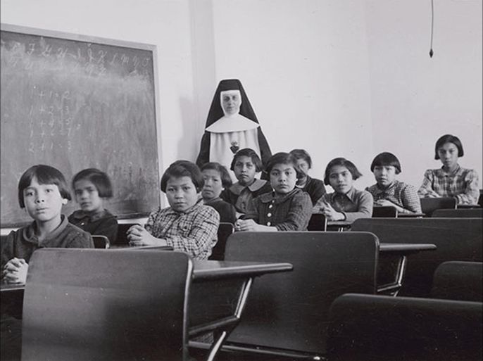 A group of female students and a nun pose in a classroom at Cross Lake Indian Residential School in Cross Lake, Manitoba in a February 1940 archive photo