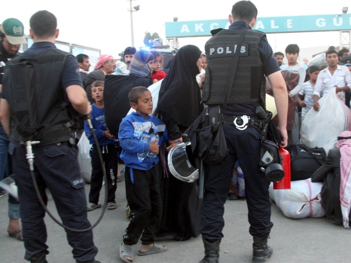 لاجئون سوريون من تل أبيض بعد عبورهم الحدود التركية فرارا من المعارك (رويترز)