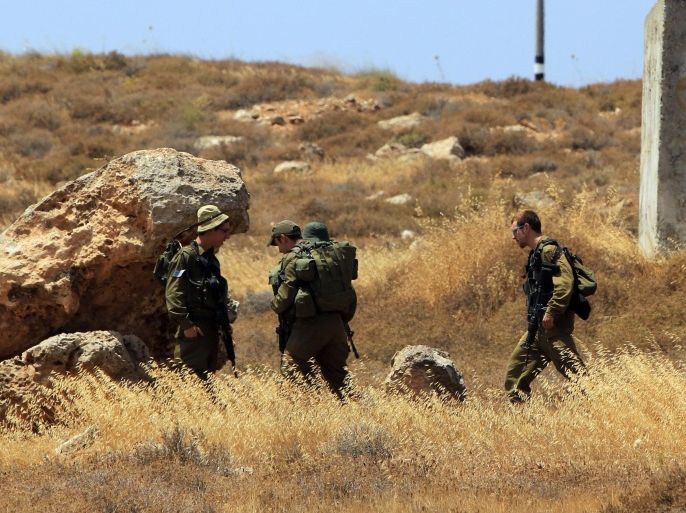 Israeli soldiers inspect the site of an attack that left four Israeli hurt, when their car came under fire, near the West Bank settlement of Shvut Rachel on June 30, 2015. The shots were fired at a crossroads near the settlement in the northern West Bank, and, despite the army's setting up of roadblocks, the perpetrator or perpetrators got away. AFP PHOTO / JAAFAR ASHTIYEH