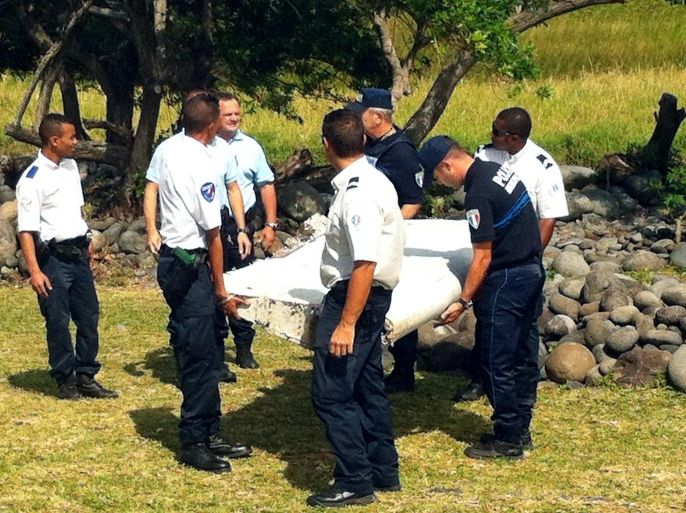 Police and gendarmes carry a piece of debris from an unidentified aircraft found in the coastal area of Saint-Andre de la Reunion, in the east of the French Indian Ocean island of La Reunion, on July 29, 2015. The two-metre-long debris, which appears to be a piece of a wing, was found by employees of an association cleaning the area and handed over to the air transport brigade of the French gendarmerie (BGTA), who have opened an investigation. An air safety expert did not exclude it could be a part of the Malaysia Airlines flight MH370, which went missing in the Indian Ocean on March 8, 2014. AFP PHOTO / YANNICK PITOU