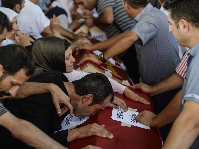 Mourners react over coffins in Gaziantep on July 21, 2015, during a funeral ceremony for victims following a suicide bomb attack the day before which killed at least 31 in the southern Turkish town of Suruc. A suspected Islamic State suicide bomber killed at least 31 people in an attack on a Turkish cultural centre in the southern town of Suruc, where activists had gathered to prepare for an aid mission in the nearby Syrian town of Kobane. It was one of the deadliest attacks in Turkey in recent years and the first time the government has directly accused the IS group of carrying out an act of terror on Turkish soil. AFP PHOTO / BULENT KILIC