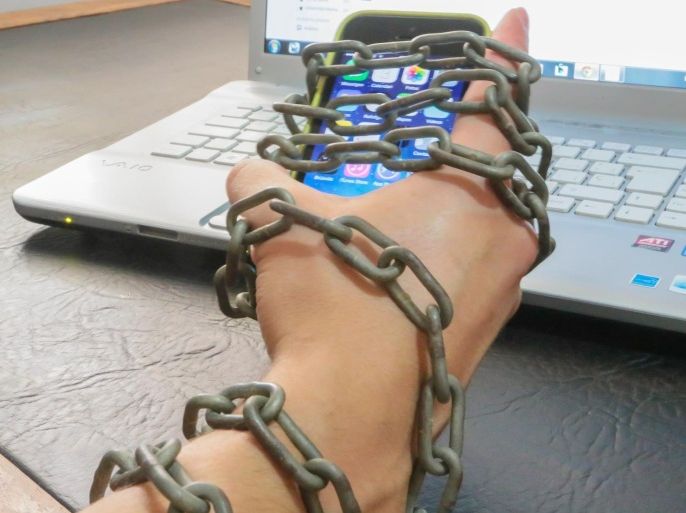 Guy chained to smartphone and internet laptop. Conceptual picture for internet addiction.