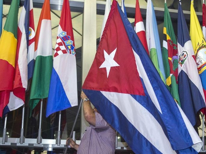 Workers at the US Department of State add the Cuban flag at to the display of flags inside the main entrance at 202 'C' Street at 4am local time (0800 GMT) in Washington, DC on July 20, 2015. The United States and Cuba formally resumed diplomatic relations on July 20, as the Cuban flag was raised at the US State Department in a historic gesture toward ending decades of hostility between the Cold War foes. AFP PHOTO / Paul J. Richards