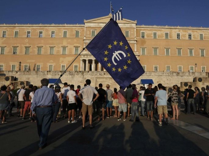 A protester holds a European Union flag with the Euro logo during a Pro-Euro rally in front of the parliament building in Athens, Greece, July 9, 2015. Greek Prime Minister Alexis Tsipras raced on Thursday to shore up political support for a tough package of tax hikes and pension reforms due within hours if Athens is to win a new aid lifeline from creditors and avoid crashing out of the euro. REUTERS/Yannis Behrakis TPX IMAGES OF THE DAY