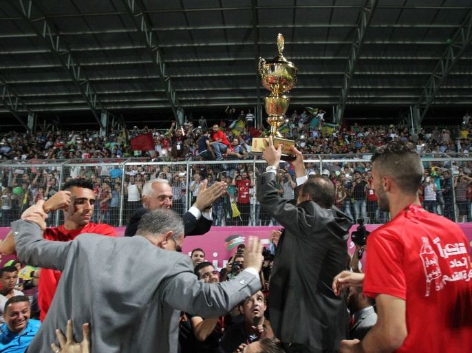 The Headoffice Manager of Al-Ahli football club lifts the trophy after a football match for the Palestine Cup final between Gaza's Chajaïya club and Hebron's Al-Ahli club on August 14, 2015 at Hussein Bin Ali Stadium in the West Bank city of Hebron. Hebron's Al-Ahli won 2-0 in a dramatic finish to the first footballing showdown in 15 years with a team from Israeli-blockaded Gaza to be proclaimed Palestinian champions. Al-Ahli will now represent Palestine, a member of football's world governing body FIFA since 1998, in international