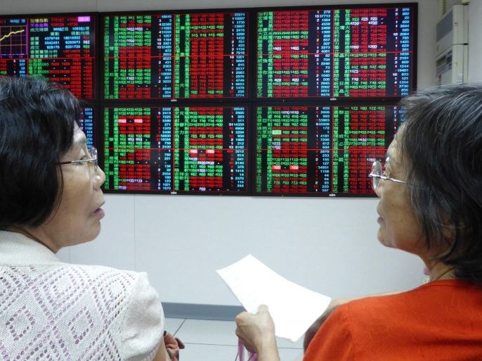 Two women discuss stocks while watching the Taiwan Stock Exchange (TAIEX) data on an electronic board at a brockerage in Taipei, Taiwan, 26 August 2015. On 26 August, following the 'Black Monday' of global stock markets' slump, Asian stock markets remained volatile after China cut its interest rate on 25 August.