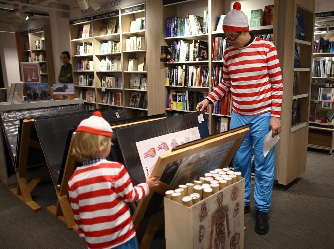 LONDON, ENGLAND - JULY 25: A father and son dressed as 'Where's Wally?' characters, also known as 'Where's Waldo?' in North America, take part in a competition to find Wally and his dog Woof at Foyles Bookstore on July 25, 2015 in London, England. The event marked the opening of 'Foyles Summer of Fun!' children's book festival where children's stories will be brought to life with immersive theatre experiences, making workshops and character visits from the likes of Shaun the Sheep and other popular children's characters.